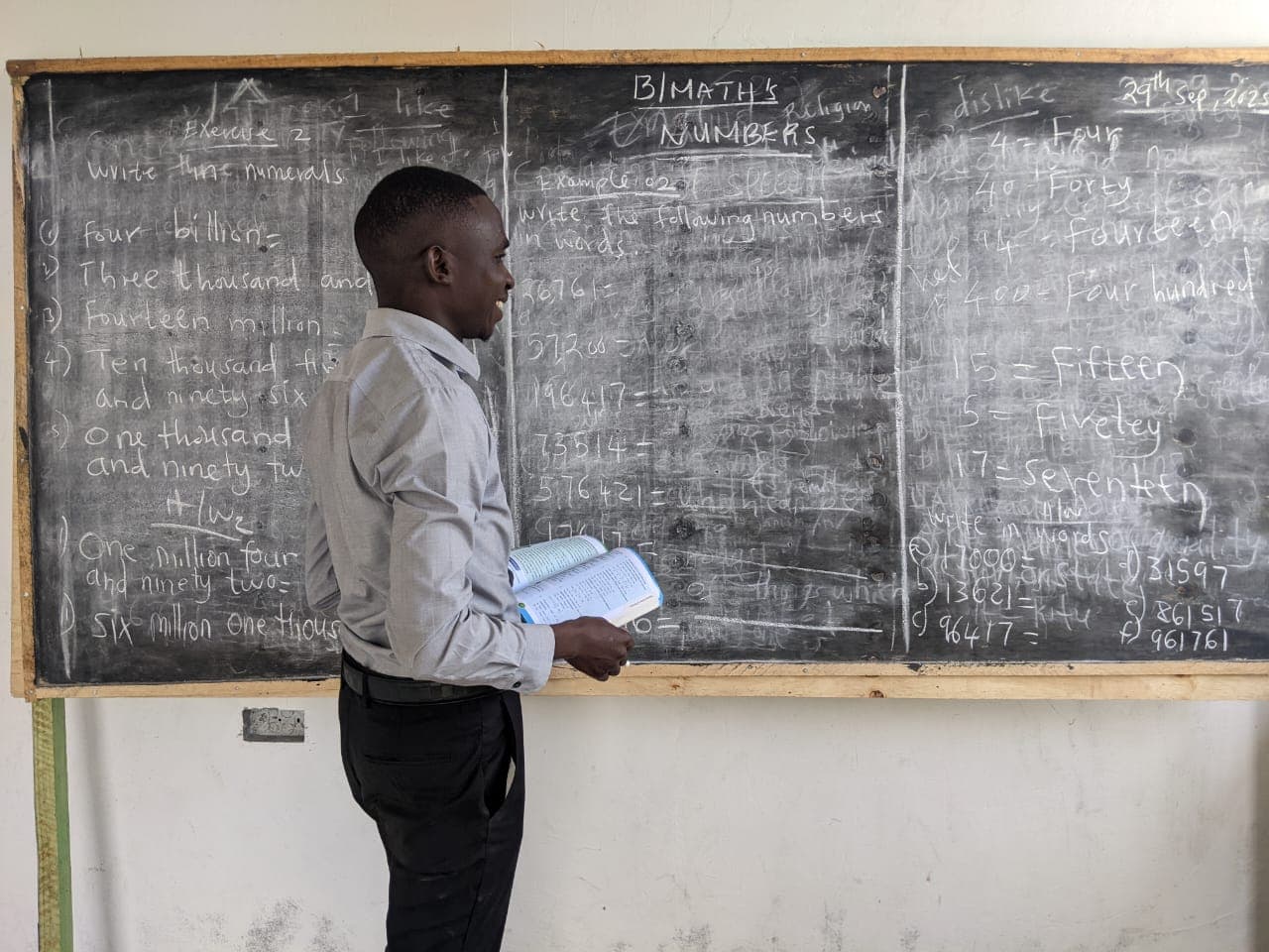 Amosi Schools teacher explaining a lesson in front of the classroom chalkboard